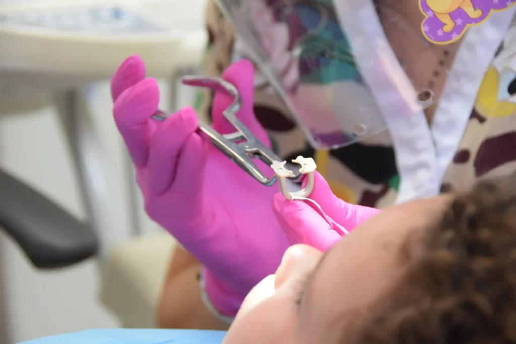 Dentista a realizar procedimento dentário em paciente infantil.