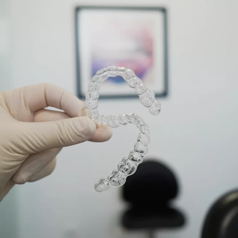 Pessoa a segurar aparelho ortodôntico transparente, conhecido como Invisalign.